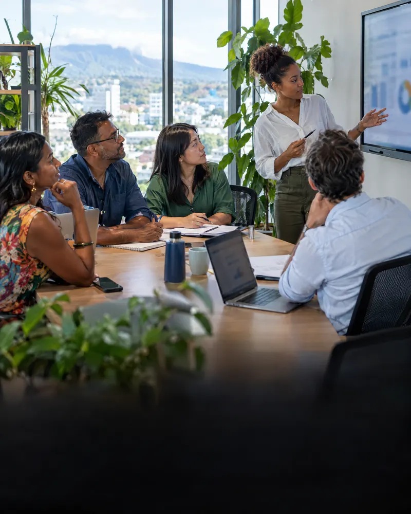 Réunion d'équipe dans une PME, une collaboratrice présente des graphiques sur un écran